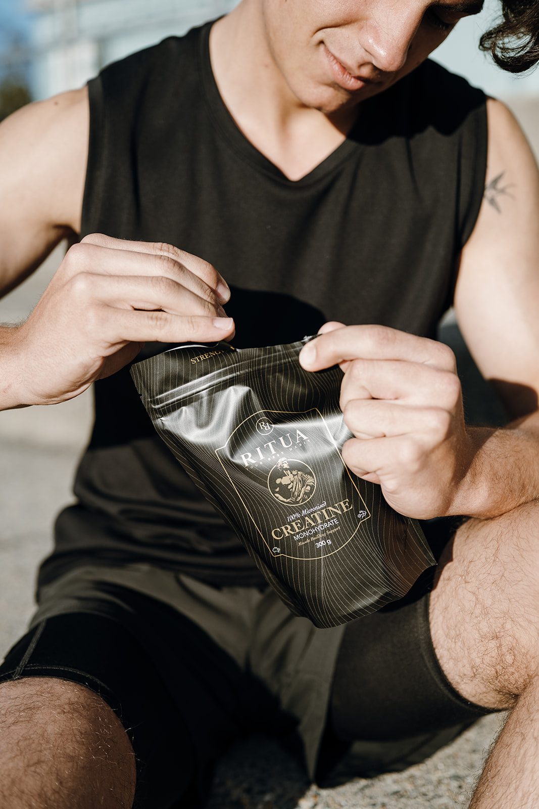 Man in training gear opening a 300g pouch of Ritua Creatine Monohydrate
