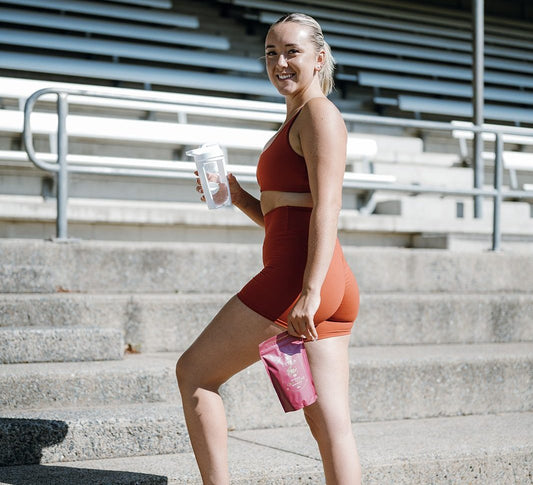 Woman in activewear on stadium steps holding a pouch of Ritua Creatine for Women