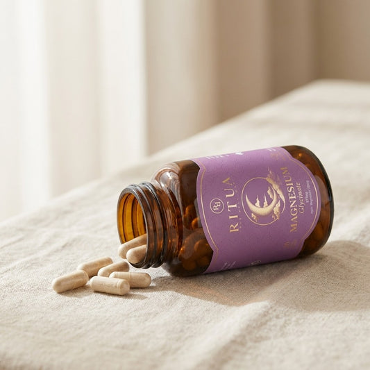 Bottle of Ritua Magnesium Glycinate on its side with capsules spilled onto linen