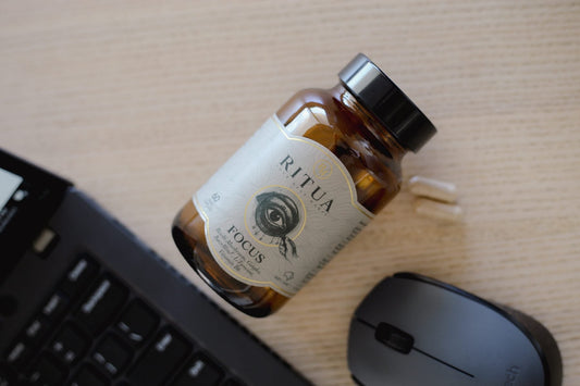 Bottle of Ritua Focus capsules on a desk beside a keyboard and mouse